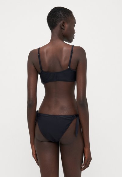 Black bikini set featuring a bandeau top with adjustable straps and matching tie-side bottoms, made from a smooth, stretchy material.