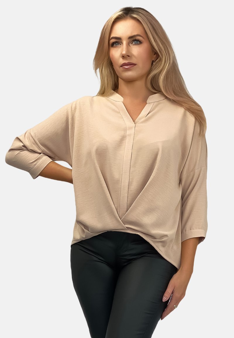 Jasnobiała bluzka z dekoltem w serek i rękawami do łokcia, z przodu z węzłem. Połączona z czarnymi, dopasowanymi spodniami.