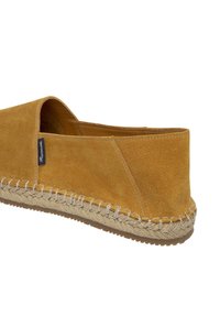Zapato marrón de ante tipo mocasín con laterales elásticos y suela de cuerda de yute trenzada, con una textura suave y líneas limpias.