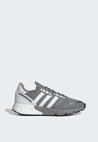 Šedé športové topánky s mesh zvrškom, tromi bielymi pruhmi a textúrovanou gumovou podrážkou. Obsahujú polstrovanú pätu a šnurovací dizajn.