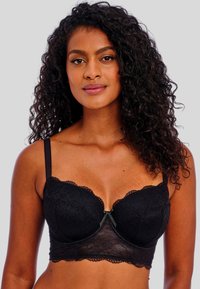 Sostén negro de encaje con aros, bordes festoneados, tirantes ajustables y un pequeño lazo en el centro. Tela suave y texturizada.