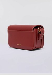 Borsa a tracolla rettangolare in pelle rossa con chiusura a patta e una fibbia dorata sul lato, esposta su uno sfondo chiaro e semplice.