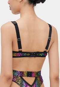 Bikini à imprimé serpent multicolore avec des bretelles noires réglables et des fermoirs au dos. Le dégradé de couleurs présente des nuances de rose, violet et vert.