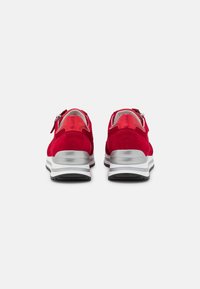 Zapatillas de ante rojas con acentos plateados, un diseño redondeado y un material texturizado. Presentan un cierre con cremallera y una suela blanca gruesa.