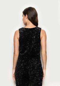 Czarny bezrękawnik z teksturowanej powierzchni pokrytej cekinami. Dopasowany krój z okrągłym dekoltem, eksponujący gładkie plecy i widoczne szwy.