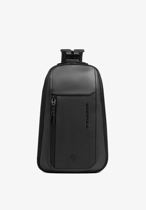 Compact zwarte schouderrugzak met gladde en gestructureerde panelen, verticale ritssluiting aan de voorkant en verstelbare riem bovenaan.