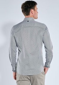 Herren Langarmhemd in Schwarz und Weiß mit geometrischem Muster, ausgestattet mit Manschettenknöpfen und einem strukturierten Kragen.