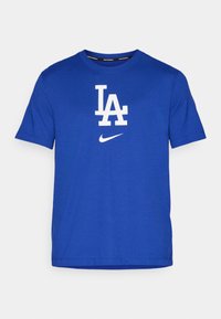 Kék pamut póló, fehér "LA" logóval és kis Nike Swoosh-sal. Rövid ujjak és kerek nyak kialakítás. Sima textúra.