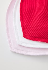 Tre mascherine in tessuto impilate: rossa con texture a righe, bianca e rosa chiaro con texture liscia, tutte con bordi rifiniti.