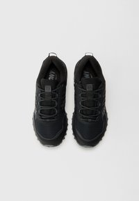 Des chaussures de sport noires présentent une tige en mesh, des accents texturés, des lacets et des semelles en caoutchouc résistantes avec des motifs de traction distincts.