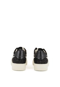 Baskets noir et blanc avec un talon texturé à paillettes noires, une tige lisse noire et une semelle en caoutchouc crème, présentant un design profilé bas.