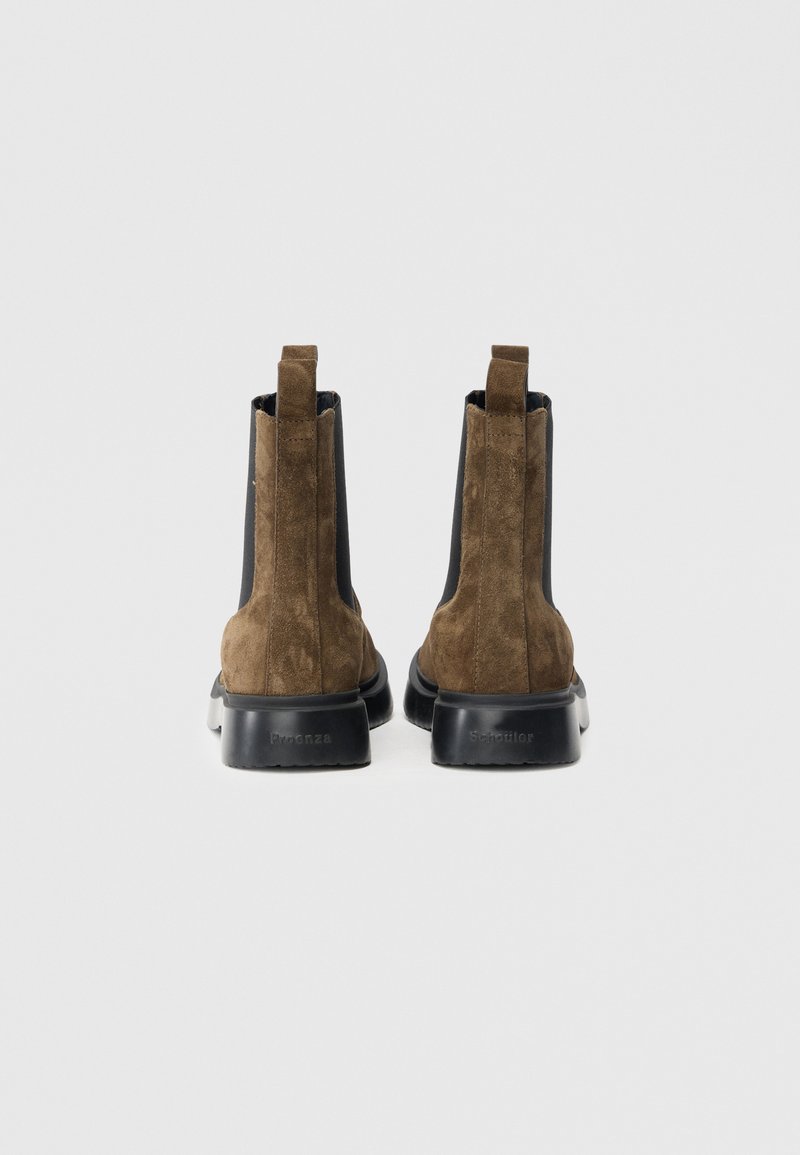 Stivaletti Chelsea in camoscio marrone con pannelli elastici neri e suola in gomma spessa. Dotati di un'asola sul retro per facilitarne la calzata.