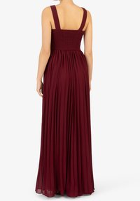 Burgundy maxiklänning med breda axelband, riktigt smockad liv och flödande, plisserad kjol, tillverkad av lättviktig tyg för komfort och rörelse.