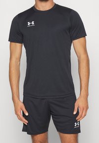 Zwart sportshirt en shorts gemaakt van lichtgewicht stof; heeft een ronde halslijn, korte mouwen en een wit logo op de borst.