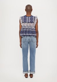 Top peplum con estampado floral y mangas con volantes; colores azul marino, rosa y blanco; combinado con jeans de pierna recta de tiro alto en azul claro.