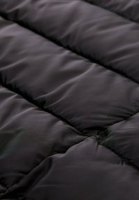 Zwarte pufferstof met een quiltontwerp, voorzien van horizontale secties gevuld met zachte isolatie en een gladde, glanzende textuur.