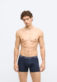 Cuecas boxer azul-marinho com tecido macio e elástico e uma cintura preta com o logótipo "Calvin Klein" em branco.