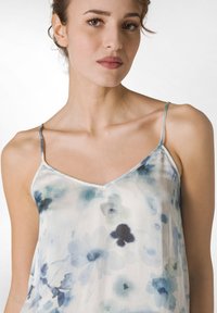 Camisola di seta floreale con scollatura a V, sottili spalline e un motivo ad acquerello nei toni del blu, verde e bianco.