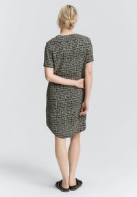 Robe à manches courtes avec un motif abstrait noir et blanc, dotée d'un ourlet arrondi et d'une coupe décontractée, fabriquée en tissu doux et léger.