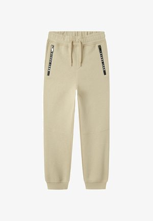 Pantalons de survêtement beige en tissu doux, avec une taille à cordon de serrage et deux poches latérales zippées noires avec logo imprimé.