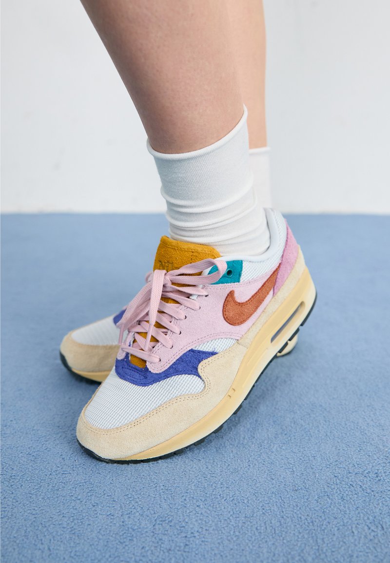 Multicolore Nike Air Max sneakers met een combinatie van suede en mesh materialen, met roze, blauw, oranje en beige accenten.