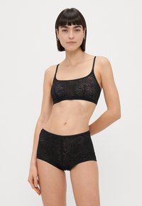 Conjunto de lingerie preto composto por um sutiã ajustado com decote quadrado e calções de cintura alta a condizer, ambos com um padrão zebrado texturizado.