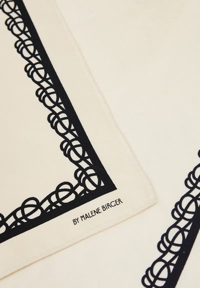Tissu de couleur crème avec un motif de bordure noire complexe en boucle et « BY MALENE BIRGER » imprimé en noir dans un coin.