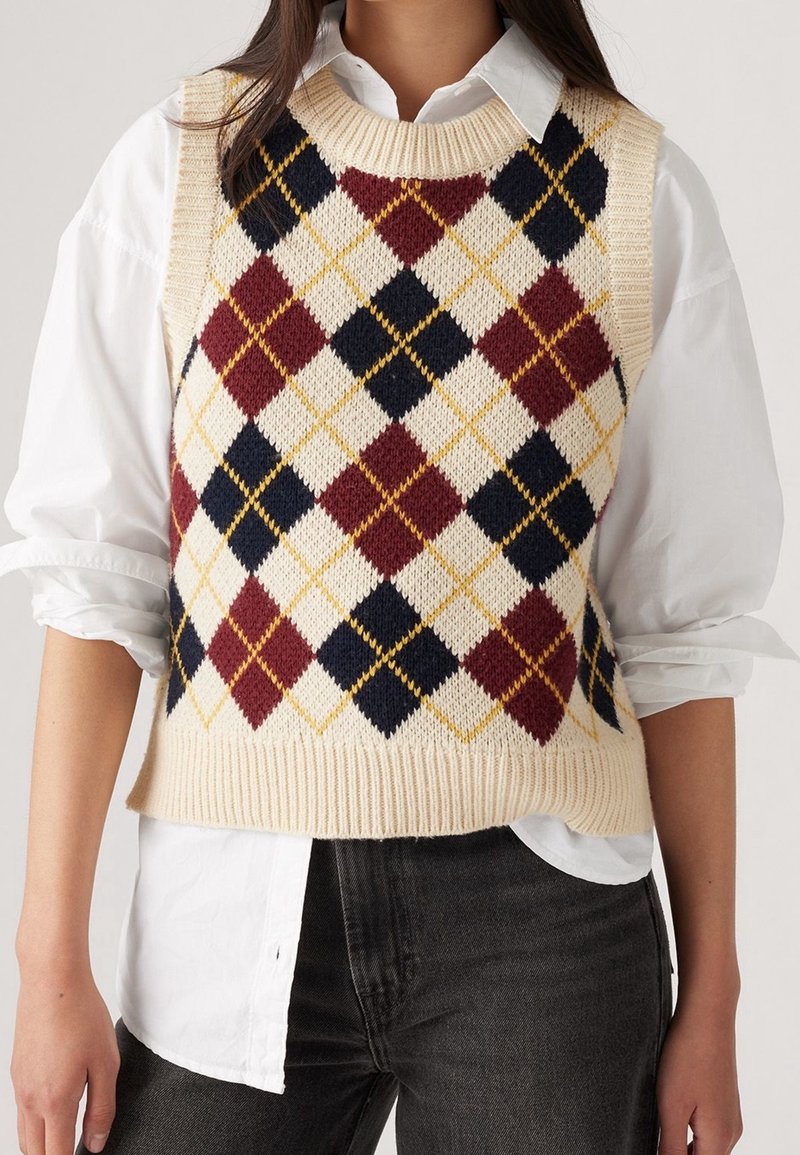 Gilet en tricot avec une base crème et un motif losanges multicolores en bordeaux, bleu marine et jaune. Encolure et ourlet côtelés, design sans manches.