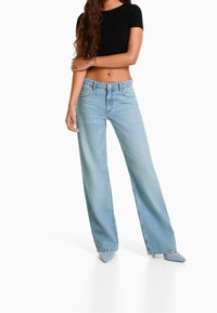 Light blue wide-leg jeans made of denim, with a high waist, five pockets, and subtle fading. Paired with a ribbed black cropped top.