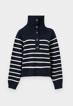 Tumši zils adīts džemperis ar baltām horizontālām svītrām, augstu ribotu apkakli un pieciem brūniem pogām priekšpusē.