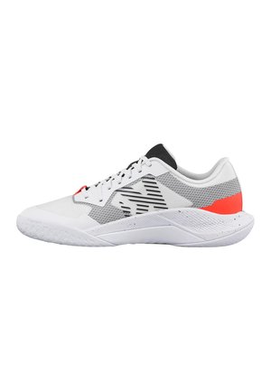 Zapatilla deportiva blanca con detalles de malla negra y gris, acento rojo en el talón, lengüeta negra y cordones blancos, mostrada de lado sobre un fondo blanco.