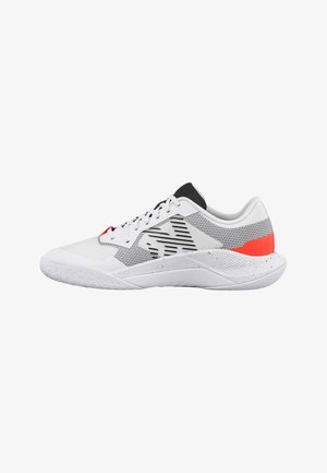 Zapatilla deportiva blanca con detalles de malla negra y gris, acento rojo en el talón, lengüeta negra y cordones blancos, mostrada de lado sobre un fondo blanco.