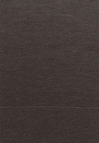 Gros plan d’un tissu tricoté brun foncé montrant de fines mailles verticales et une couture horizontale près du bas.