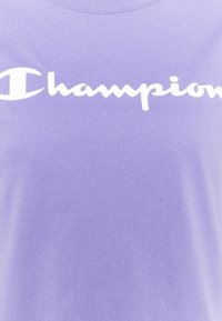 Lila bomull t-shirt med en framträdande vit "Champion"-logga över bröstet. Slät textur med en klassisk rund halsringning.