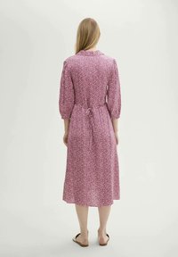 Rosa Blumen-Kleid mit einem Taillengurt, dreiviertellangen Puffärmeln und einem knielangen Design. Das Material wirkt leicht und hat eine weiche Textur.
