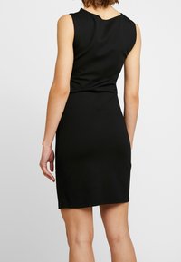 Svart ärmlös klänning med en åtsittande siluett, med rund halsringning, slät yta och knälång fåll.