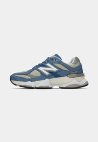 Blue and gray athletic sneaker with white sole, mesh panels, suede overlays, and a large white "N" logo on the side.