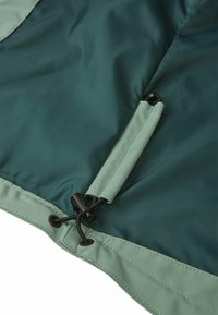 Ourlet de veste vert foncé avec cordon de serrage ajustable et bascule en plastique pour resserrer l'ajustement.