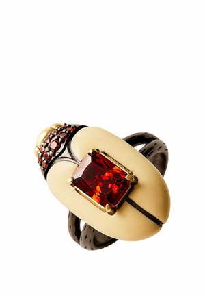 Anillo con pieza central ovalada de color crema, gran piedra preciosa roja rectangular en engaste de oro y banda oscura con pequeñas piedras rojas.