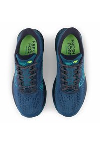 Blaue Mesh-Laufschuhe mit grünen Akzenten. Merkmale sind ein strukturiertes Obermaterial, gepolsterter Kragen und gemusterte Schnürsenkel, gekennzeichnet mit "Fresh Foam" und "Gore-Tex".