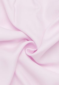 Lys pink stof med en glat tekstur, der viser en subtil glans, arrangeret i bløde folder, som fremhæver dens faldende kvalitet.