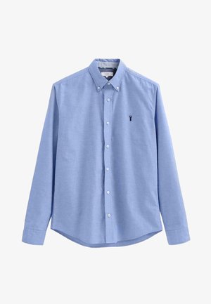 Camisa de botón azul claro con mangas largas, cuello extendido y un pequeño emblema de langosta en marino en el lado izquierdo del pecho. Tejido suave, corte entallado.