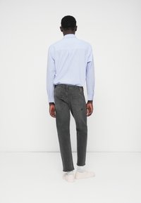 Ανδρικό ανοιχτό μπλε ριγέ πουκάμισο συνδυασμένο με σκούρο γκρι τζιν. Διαθέτει στενή εφαρμογή, καμπυλωτό πίσω τελείωμα και δύο πίσω τσέπες. Απαλά παπούτσια.