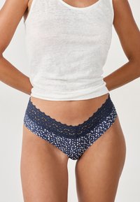 Mutande navy con pizzo, decorate con un motivo a cuori bianche, realizzate in materiale morbido, con un design della vita scallop.