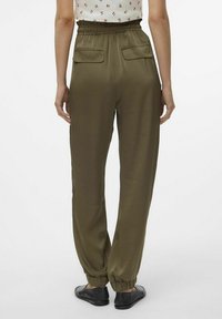 Pantalon vert olive avec une coupe décontractée, taille élastique et chevilles froncées. Il dispose de deux poches arrière et est fabriqué dans un tissu lisse et léger.