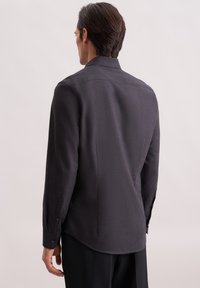 Camicetta da uomo grigio scuro a maniche lunghe con una sottile texture, polsini con bottoni e una vestibilità attillata, che presenta un yoke splittato e un orlo arrotondato.