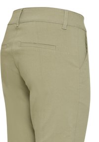 Pantalon beige avec passants pour ceinture et deux poches passepoilées à l'arrière, vu de l'arrière côté droit.