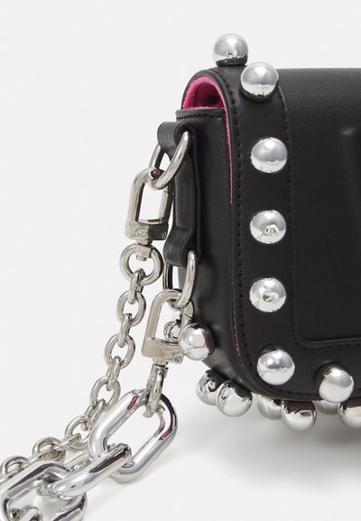 Close-up of black leather bag corner with silver stud embellishments and thick silver chain strap with lobster clasps.