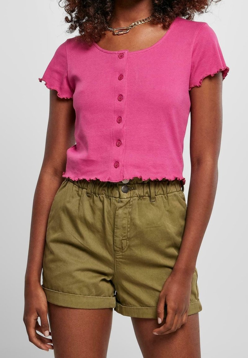 Fuksjowy krótki T-shirt z okrągłym dekoltem i krótkimi falbaniastymi rękawami, ozdobiony rzędem guzików. Połączony z oliwkowozielonymi podwiniętymi szortami.