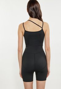 Body nero con spalline sottili, caratterizzato da una texture liscia, un design aderente che si estende fino a metà coscia e dettagli di cucitura sottili.